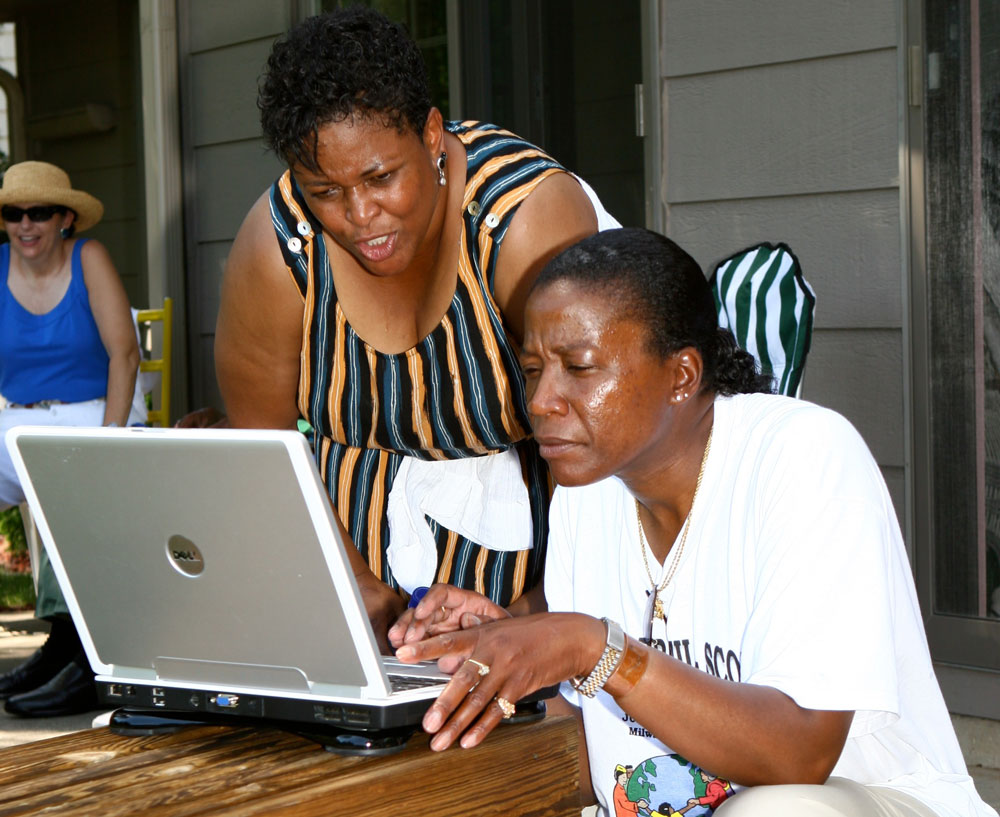 Exploring family history at the McNair Brazil Scott Family Reunion in Milwaukee, Wisconsin. Cousins Candace Wilcher (left, Brazil branch) and Shelley Mathews (McNair branch) take the opportunity of the reunion to review family genealogy. 