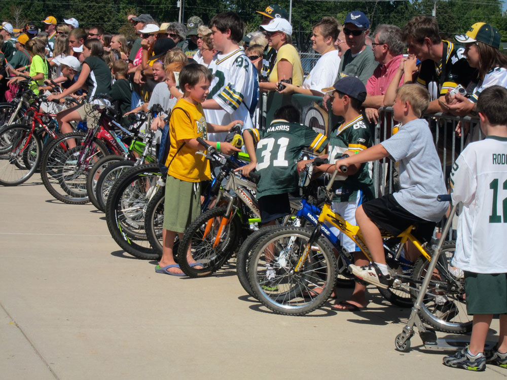 Kids line up hoping a Packer, coming from the locker room, will want to ride their bike or scooter to the practice field several blocks away.